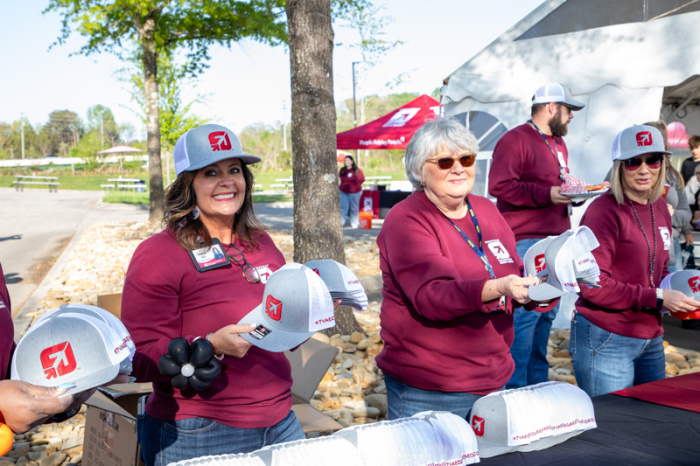 Three KTVAECU employees handing out hats to members as they exit Annual Meeting 2025
