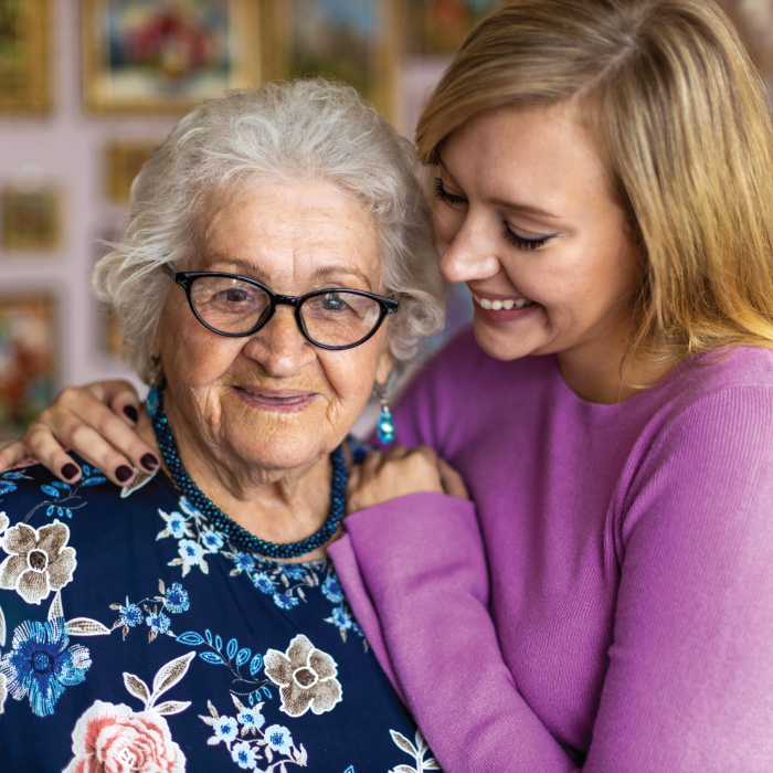 senior woman being hugged by younger woman