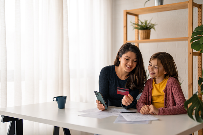 Mom and daughter looking at debit card and smiling