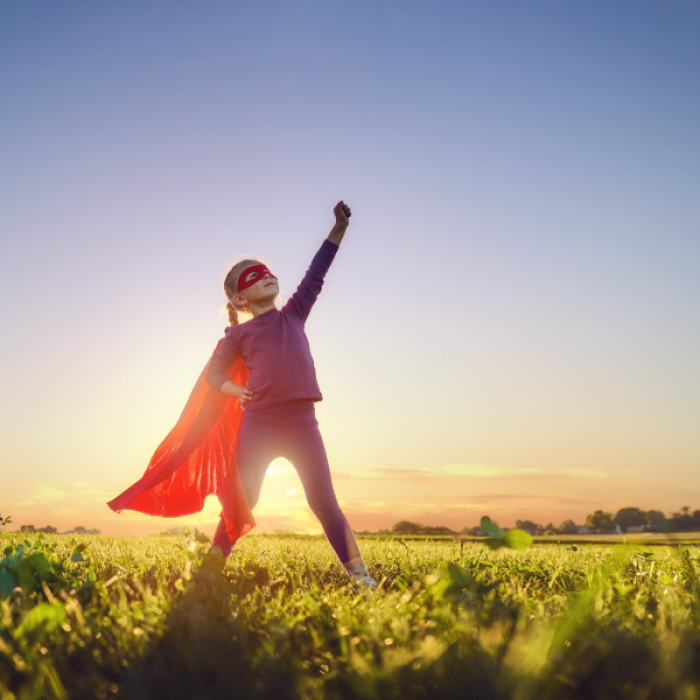 child in super hero costume with cape