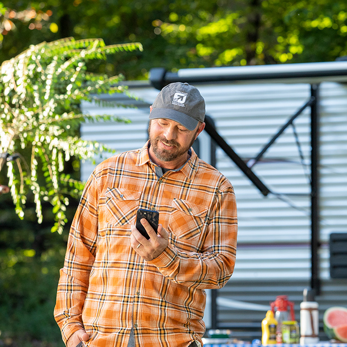 Man camping and looking at his cell phone.