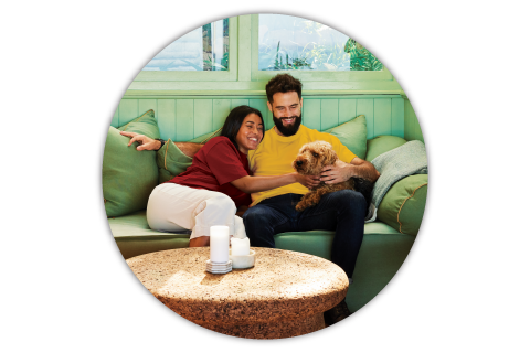 Young couple sitting on couch and petting dog