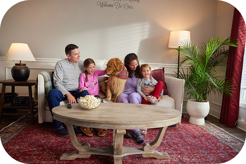 Family of four relaxing in living room with dog