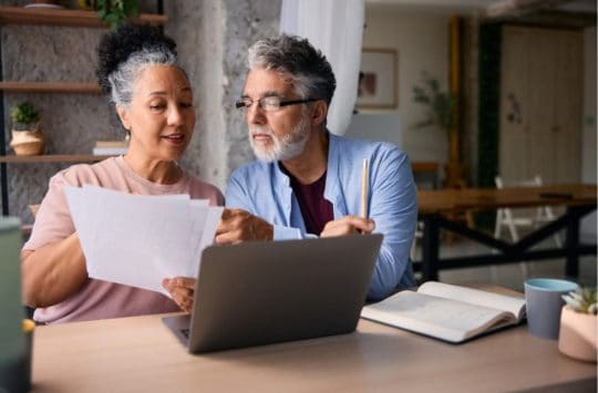 Older couple sitting in front of a computer planning their budget.