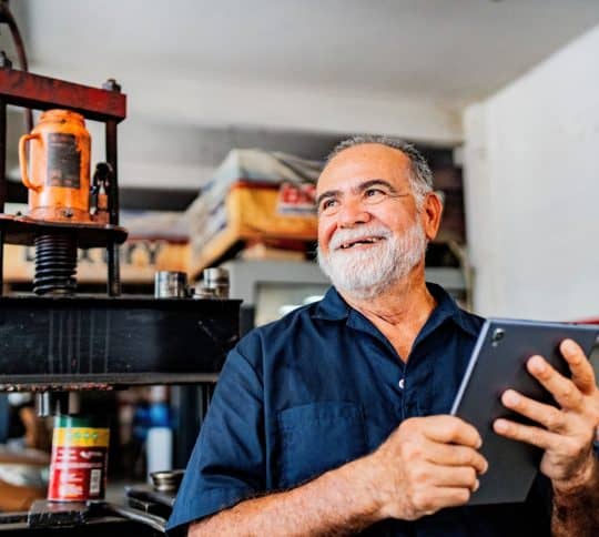 Man holding iPad and smiling in industrial shop