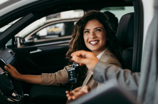 Woman sitting in driver's seat of the car about to receive her new car keys