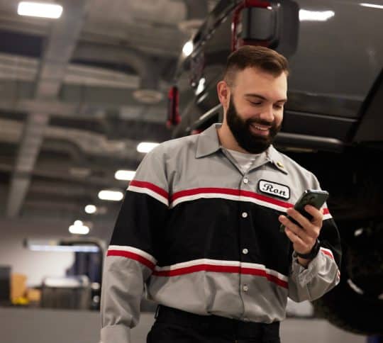 Man checking cell phone in car shop