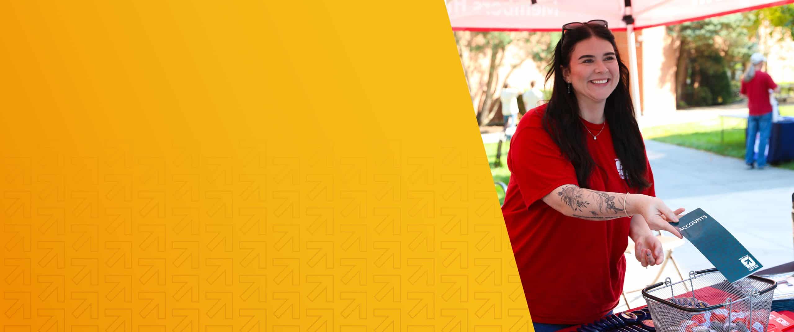 Smiling woman at community event with a red shirt and tattoos.