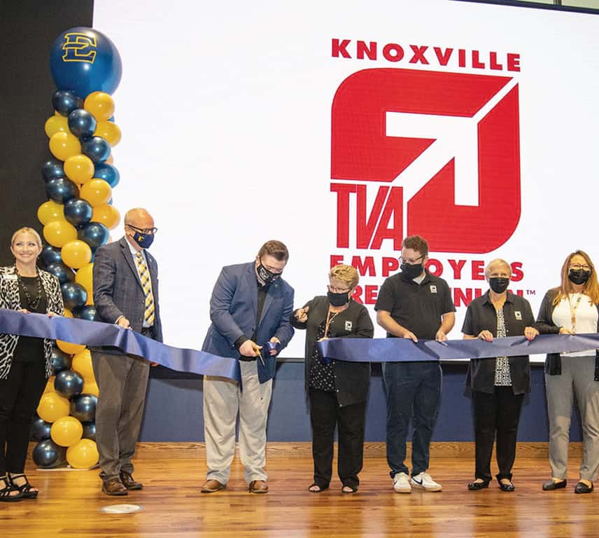 ETSU and KTVAECU staff members standing on a stage cutting a ribbon