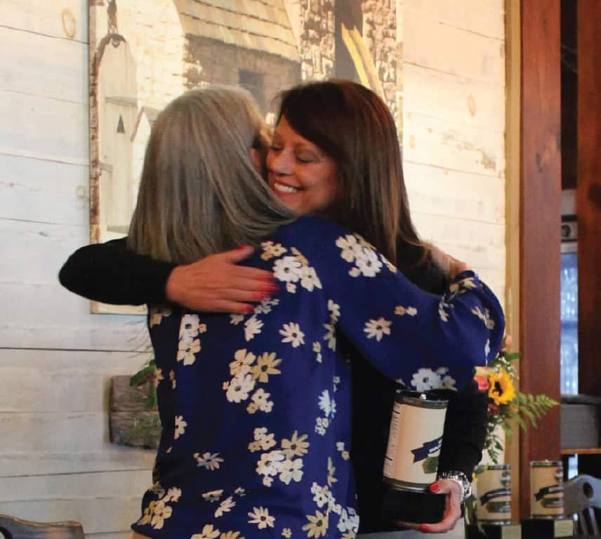 KTVAECU CEO Lynn Summers hugging Second Harvest Employees while accepting an award