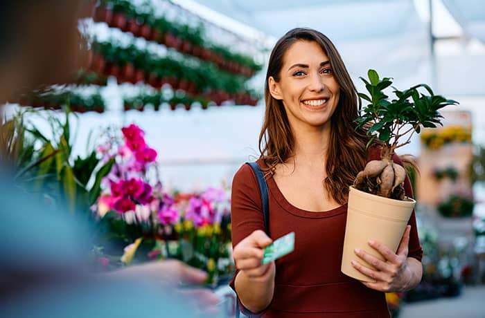 Young woman purchasing a plant with a credit card.