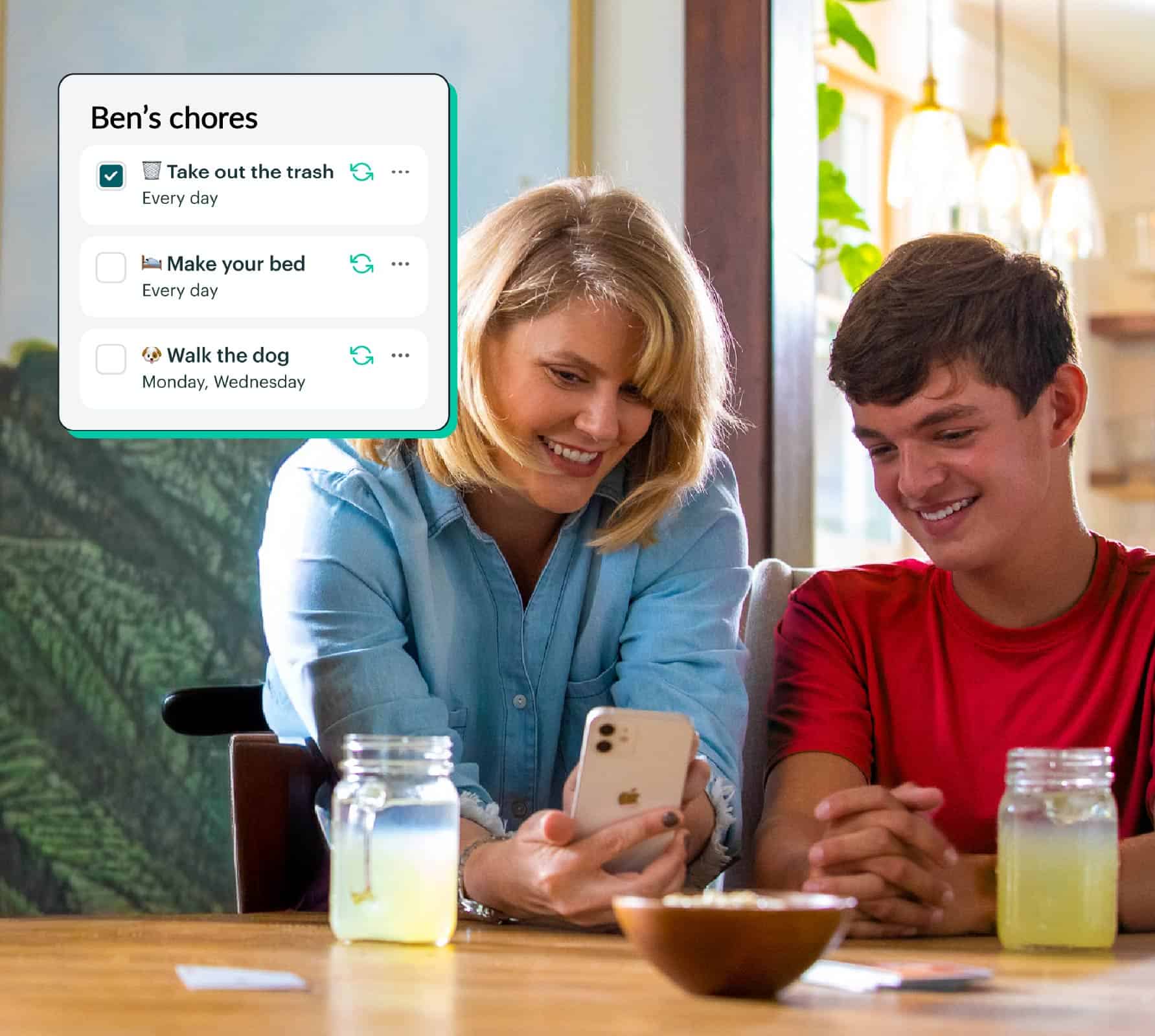 Parent and child using a smartphone to check chores list in the Greenlight app.