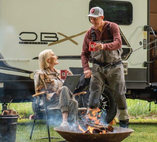 Couple sitting at a campfire with KTVAECU mugs
