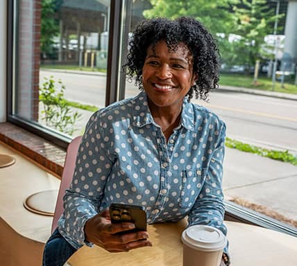 Lady on her phone with a coffee in her hand