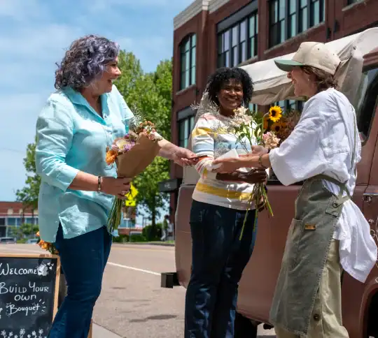 Woman running flower truck giving out bouquets to customers