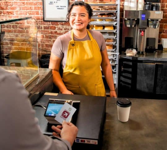 Man using KTVAECU debit card at a coffee shop register