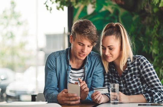 Male friend teaching his female friend about debit card features.