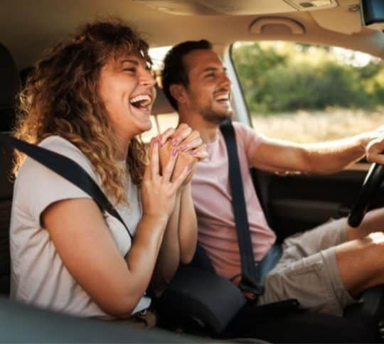 Couple traveling in car laughing and smiling