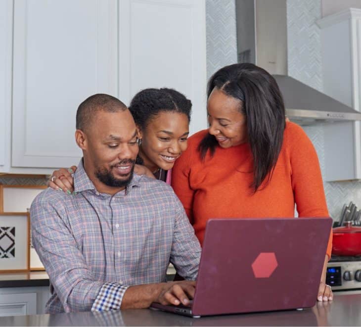 Family sitting at kitchen counter on their laptop