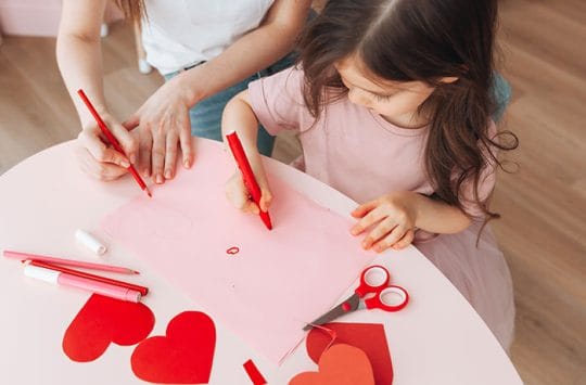 Mom and daughter doing Valentine's Day crafts together.