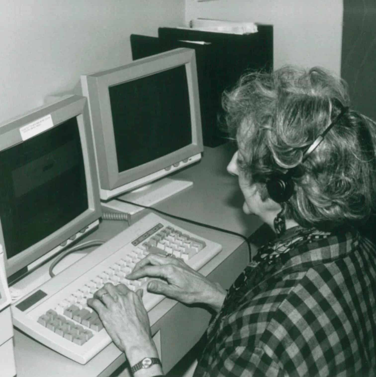 A person in front of a computer and taking a client call.