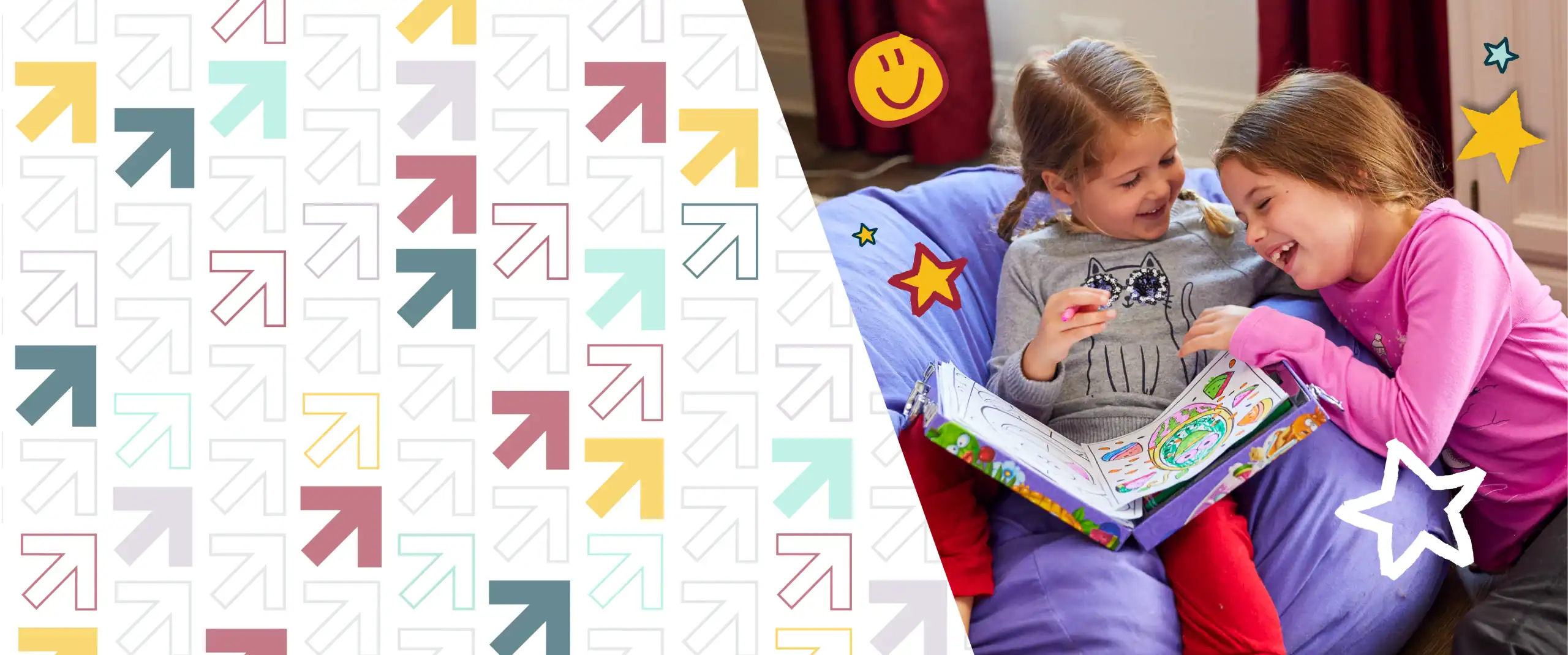 Two girls sitting down coloring and laughing.